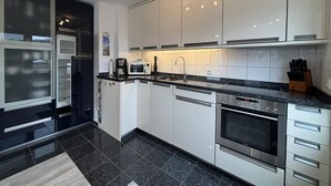 Eine moderne Küche mit weißen Schränken, einer schwarzen Arbeitsplatte, einem eingebauten Backofen und einer Mikrowelle.
