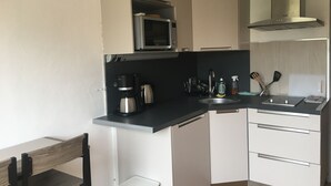 Une cuisine compacte équipée d’un four à micro-ondes, d’une machine à café, d’un évier et d’une petite poubelle.
