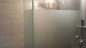 Une salle de bain moderne avec une douche à parois de verre, un meuble-lavabo en bois et un lavabo en verre.