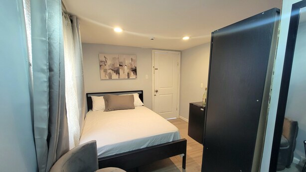 Ein Schlafzimmer mit Bett, Stuhl, Kleiderschrank und einer Tür.