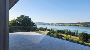 A balcony with a clear view of a lake and surrounding landscape.