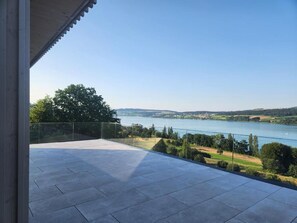 A balcony with a clear view of a lake and surrounding landscape. - Lakeview Guest Rooms Rooftop Terrace (Ebikon)