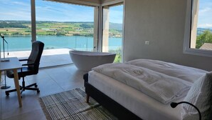 A bedroom with a bed, a desk, and a large bathtub.