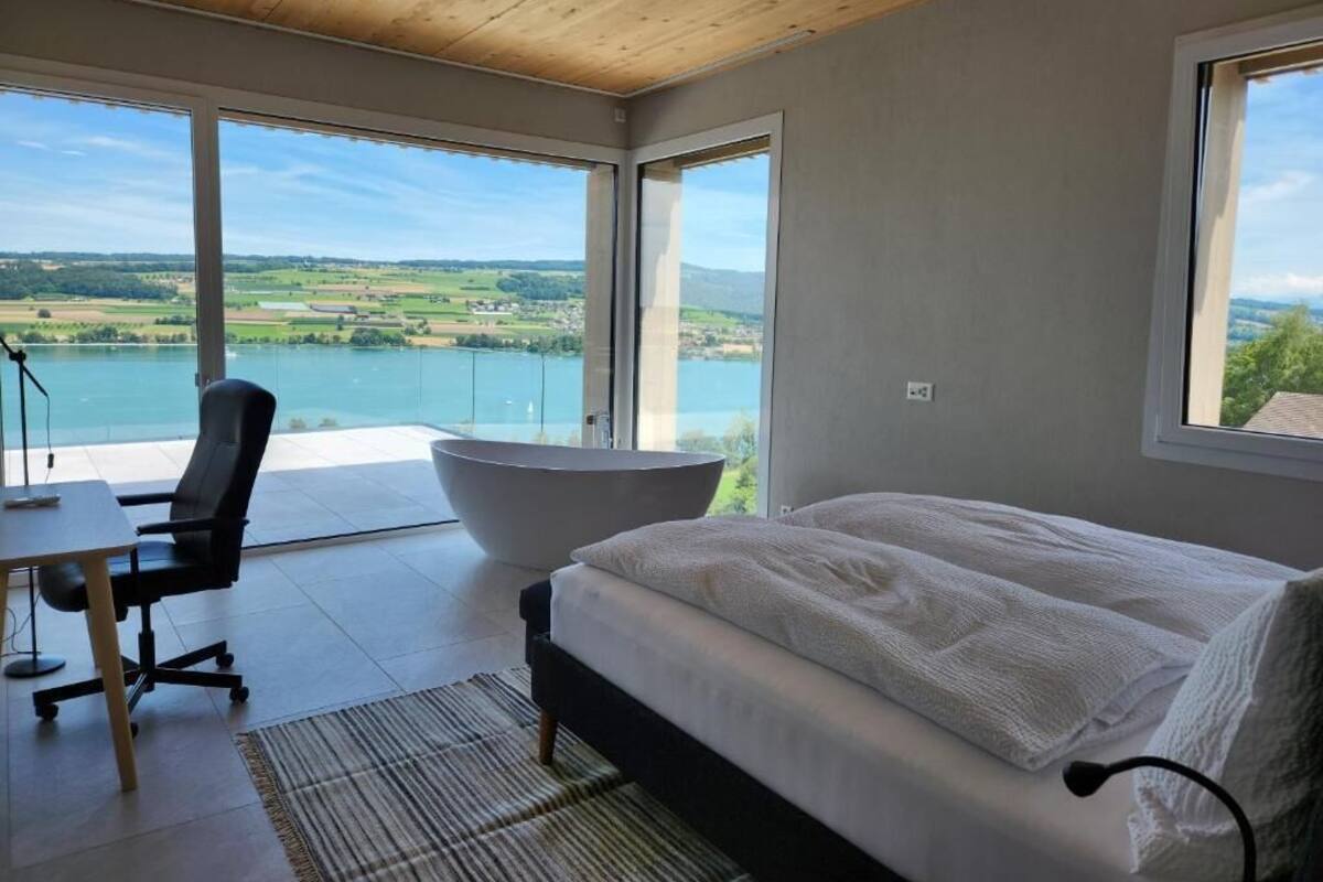 A bedroom with a bed, a desk, and a large bathtub.