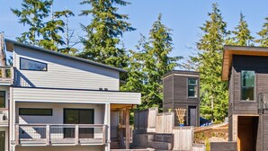A modern multi-story building with balconies, wooden fences, and a stone pathway.