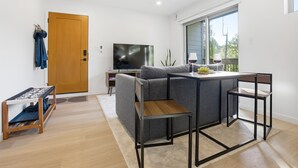 A modern living room with a grey sectional sofa, a small wooden coffee table, a TV, and a dining area with a table and chairs.