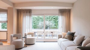 A modern living room with a sofa, armchairs, and a dining table with chairs.