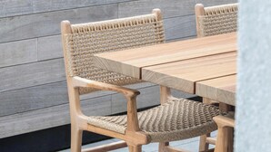 A wooden table with woven chairs.