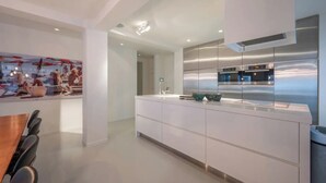 Eine moderne Küche mit Edelstahlgeräten, einer großen Kochinsel und einem Essbereich mit Holztisch und Stühlen.