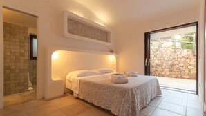 A bedroom with a bed, a shower, and a stone wall outside. - Calypso Lux Independent Villa (AGLIENTU)