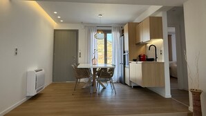 Uma cozinha moderna com armários de madeira, um espaço de jantar com mesa e cadeiras, e vista pela janela com cortinas.