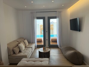 A modern living room with a sofa, ottoman, and a round coffee table. - 2-bedroom villa Odysseus (Antiparos)