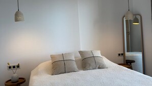 Un dormitorio con una cama grande, dos mesitas de noche, una lámpara de noche y un espejo en la pared.