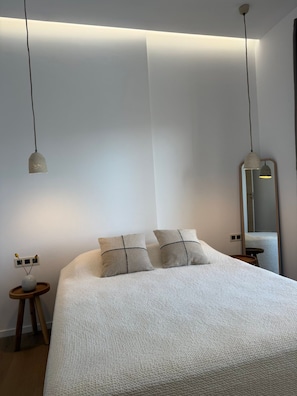 Un dormitorio con una cama grande, dos mesitas de noche, una lámpara de noche y un espejo en la pared.