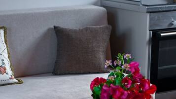 A living room with a sofa, a coffee table with a vase of flowers, a remote control, and a decorative plate.