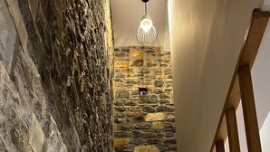 Uma escadaria de madeira com uma parede de pedra de um lado e um corrimão de madeira do outro.