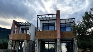 Et moderne hus med to etager, en stenfassade, store vinduer og en balkon.