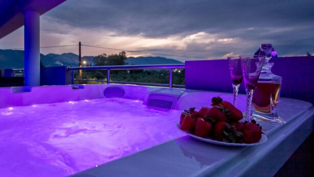 A hot tub with a view of mountains in the background, a plate of strawberries, and two glasses of a beverage. - DimArist Residence in Zakynthos (Agios Kirikos)