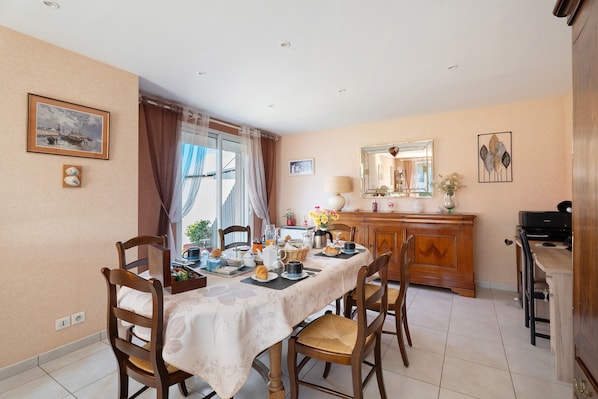 A dining area with a table set for four, chairs, a wooden cabinet, and a mirror on the wall.