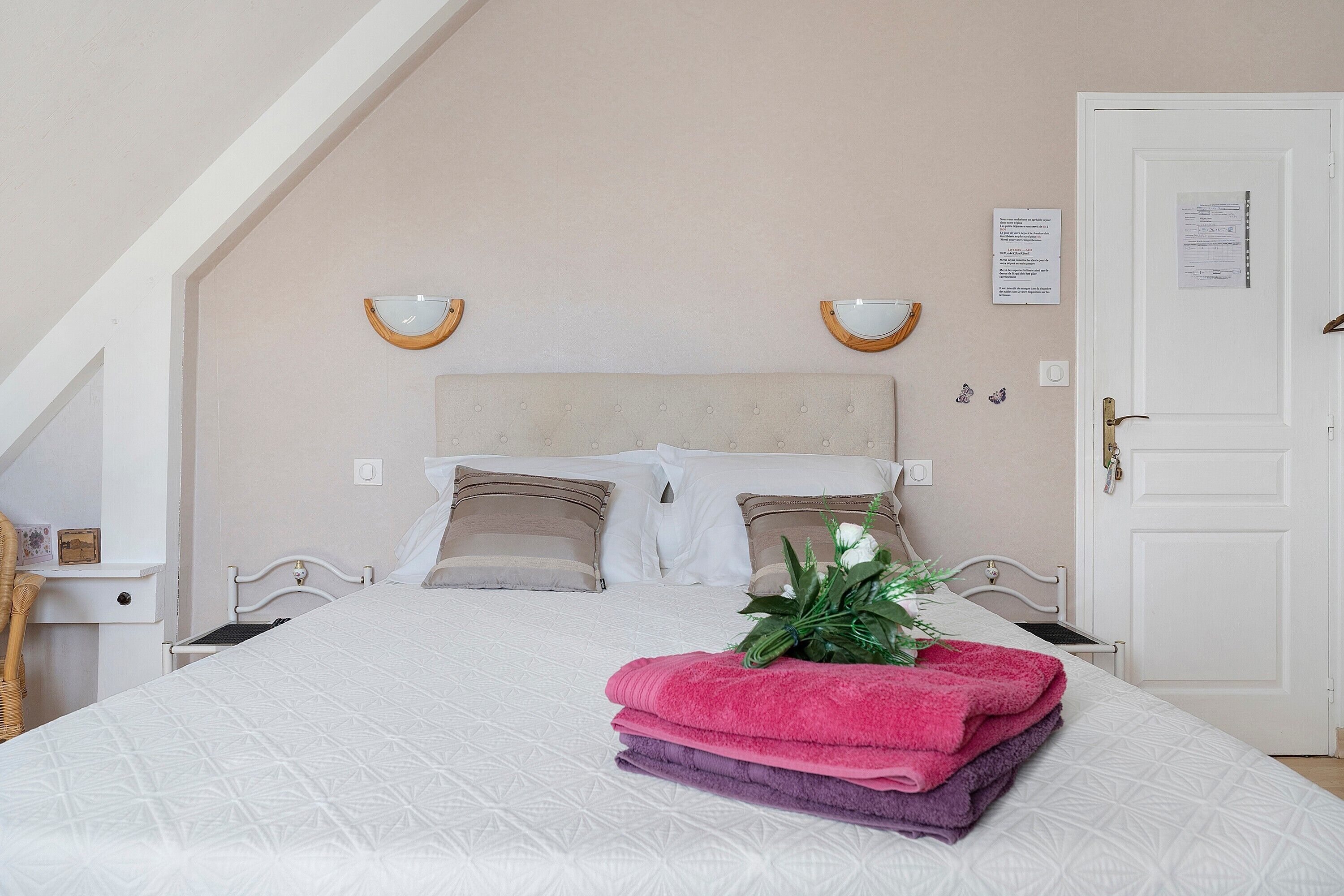 A neatly made bed with a white duvet, a headboard, and two wall-mounted lamps.