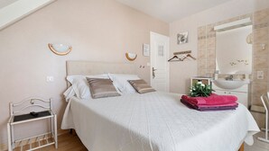 Un dormitorio con cama, mesita de noche y baño con lavamanos y espejo.