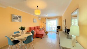 A bright living room with a sofa, a dining table with chairs, a TV, and a balcony with a view. - Sunny 2 bedroom apartment in Denia 200m from the beach (Dénia)