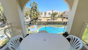 A balcony with a white table and chairs, overlooking a swimming pool and a residential area. - Sunny 2 bedroom apartment in Denia 200m from the beach (Dénia)