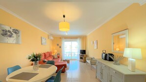 A bright living room with a sofa, dining table, chairs, and a TV. - Sunny 2 bedroom apartment in Denia 200m from the beach (Dénia)