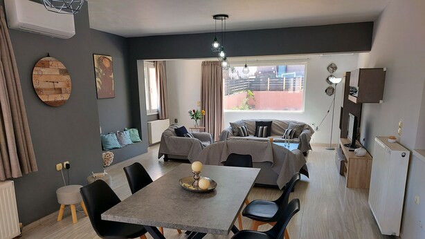 Una sala moderna con comedor, sofás grises, una mesita de centro y un ventanal con vistas.