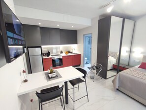 Ein kompaktes Hotelzimmer mit Küchenzeile, Essbereich und Bett.