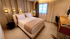 Moderni hotellihuone, jossa on suuri sänky, työpöytä ja tuoli.