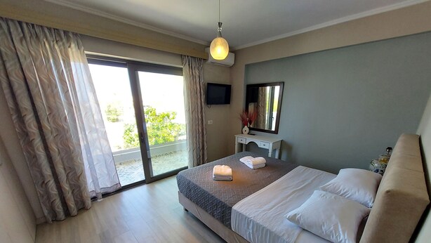 A hotel room with a bed, a TV, a desk, and a view of the outdoors. - Rethymno Suburb Maisonette (Rethimno)