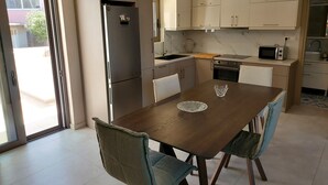 A modern kitchen with a dining area, featuring a refrigerator, microwave, oven, and a dining table with chairs. - Rethymno Suburb Maisonette (Rethimno)
