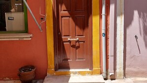 Un edificio rosso con una porta marrone, una piccola finestra e un numero 47.