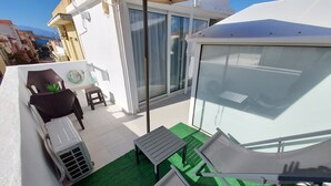 Un balcone con una divano, un tavolino e un barbecue.