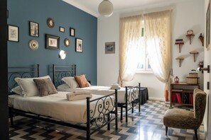 A bedroom with a bed, a chair, a bedside table, and a window with curtains. - Casa Nanna Chic in Vaticano (Rome)