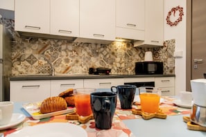 A breakfast setup with croissants, orange juice, and coffee mugs on a table with a patterned tablecloth. - Casa Nanna Chic in Vaticano (Rome)