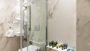 Een moderne badkamer met een douche met glazen wand, een wit toilet en een plank met toiletartikelen.