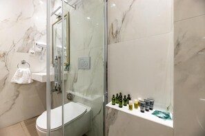 Une salle de bain moderne avec une douche à parois de verre, des toilettes blanches et un mur en marbre.