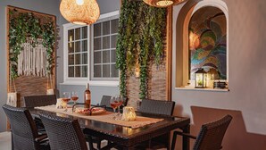 A dining area with a large table, wicker chairs, and hanging plants. - Maio Seaview & Sunset Stay in Kremasti Rhodes (Kremasti)