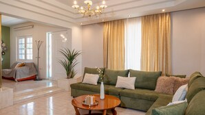 A living room with a green sofa, a wooden coffee table, and a chandelier. - Maio Seaview & Sunset Stay in Kremasti Rhodes (Kremasti)