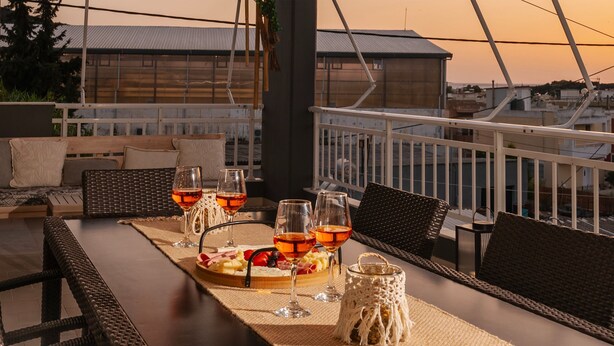 A dining area with a long table set for a meal, featuring a variety of dishes and drinks. - Maio Seaview & Sunset Stay in Kremasti Rhodes (Kremasti)