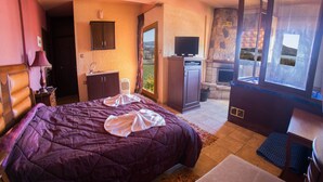 A bedroom with a large bed, a television, a fireplace, and a view of the outdoors. - Private Jaccuzzi Suite (Kryonérion, limni plastira, karditsa)