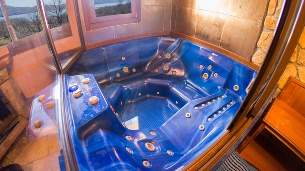 A hot tub with a view of the outdoors, a wooden bench, and a stone wall. - Private Jaccuzzi Suite (Kryonérion, limni plastira, karditsa)