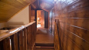 Una escalera de madera con barandilla que lleva a un dormitorio.