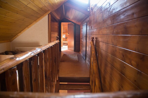 A wooden staircase leading to a bedroom with a sloped ceiling.