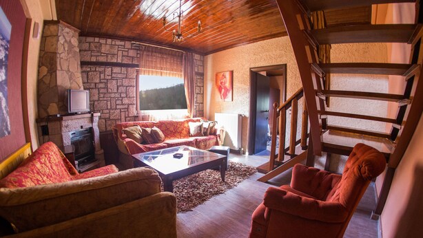 Una sala de estar acogedora con chimenea de piedra, un sofá, una mesa de centro y una escalera.