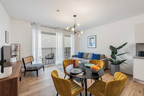 Una sala de estar moderna con comedor, un sofá y una planta grande.
