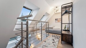 Ein modernes Schlafzimmer im Loft-Stil mit Dachfenstern, einer Metalltreppe, einem Bett, einem Nachttisch und einer eingebauten Garderobe.