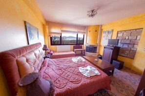Une chambre d’hôtel avec un grand lit, un petit bureau, une télévision et une cheminée en pierre.